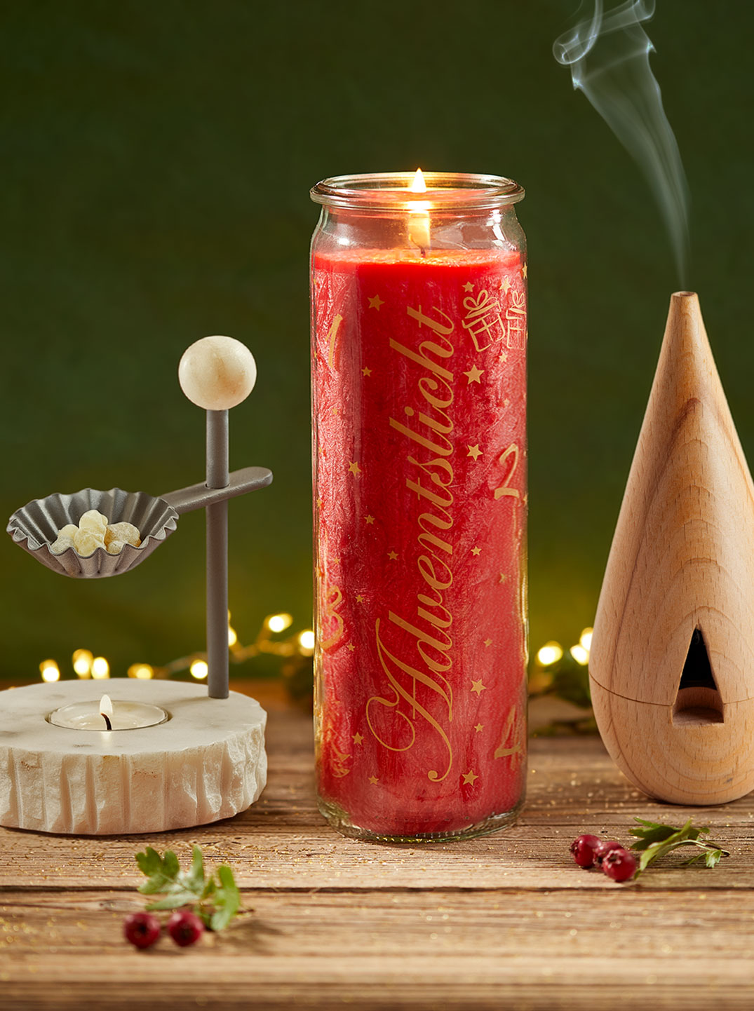 Eine leuchtend rote Kerze brennt hell, daneben ein Weihrauchstövchen und ein Räucherkegelhalter, aus dem feiner Rauch aufsteigt. Goldene Lichterketten verleihen der Szene eine festliche, warme Ausstrahlung.