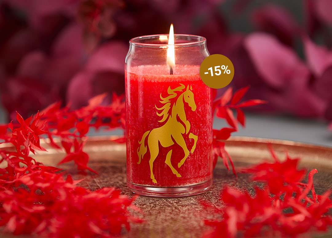 Leuchtend rote Kerze im Glas mit goldenem Pferdemotiv steht auf einem Kupferteller, umrahmt von roten Blättern – ein ausdrucksstarkes Arrangement voller Kraft, Eleganz und spiritueller Symbolik für das Jahr des Feuerpferds.