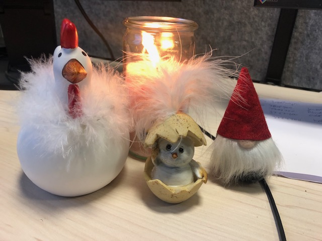 Brennende Kerze mit verschiedenen Figuren: Ein Huhn, ein Wichtel und ein Küken in der Eierschale