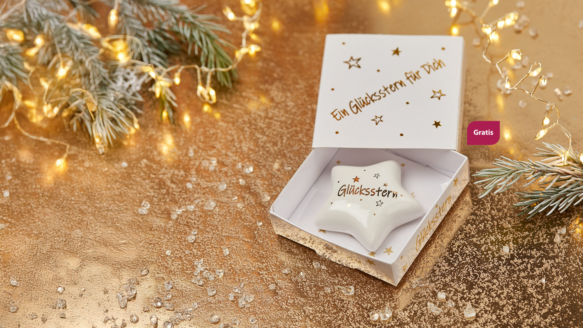 Ein kleiner fünfzackiger Stern aus weißem Porzellan mit goldener Aufschrift "Glücksstern". Daneben steht "Gratis".