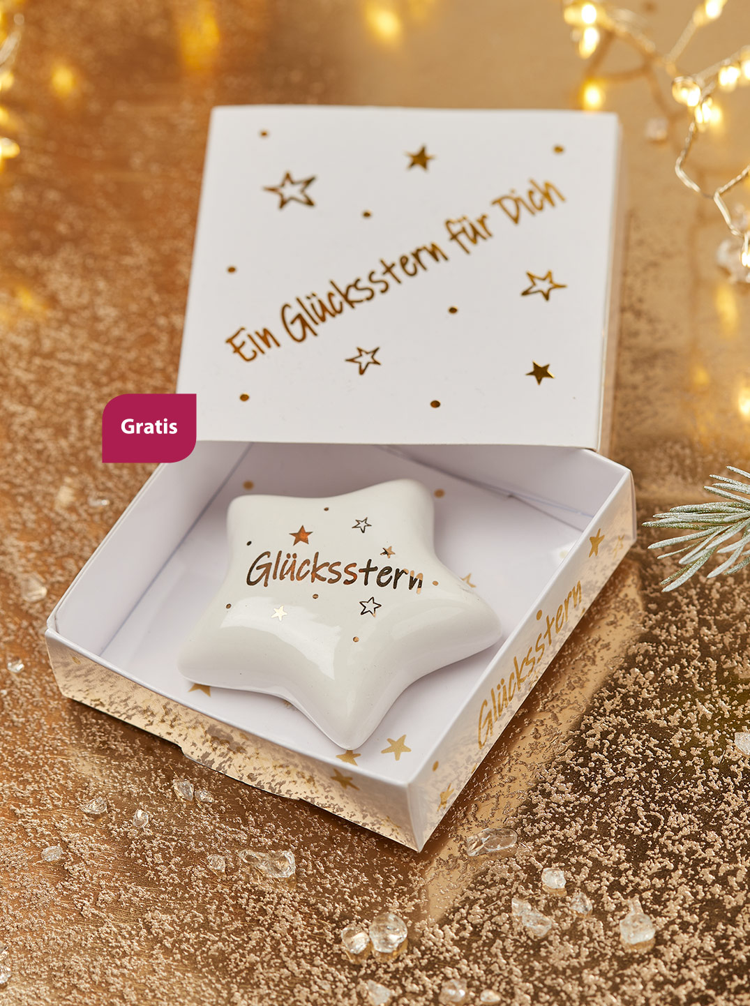 Ein kleiner fünfzackiger Stern aus weißem Porzellan mit goldener Aufschrift "Glücksstern". Daneben steht "Gratis".