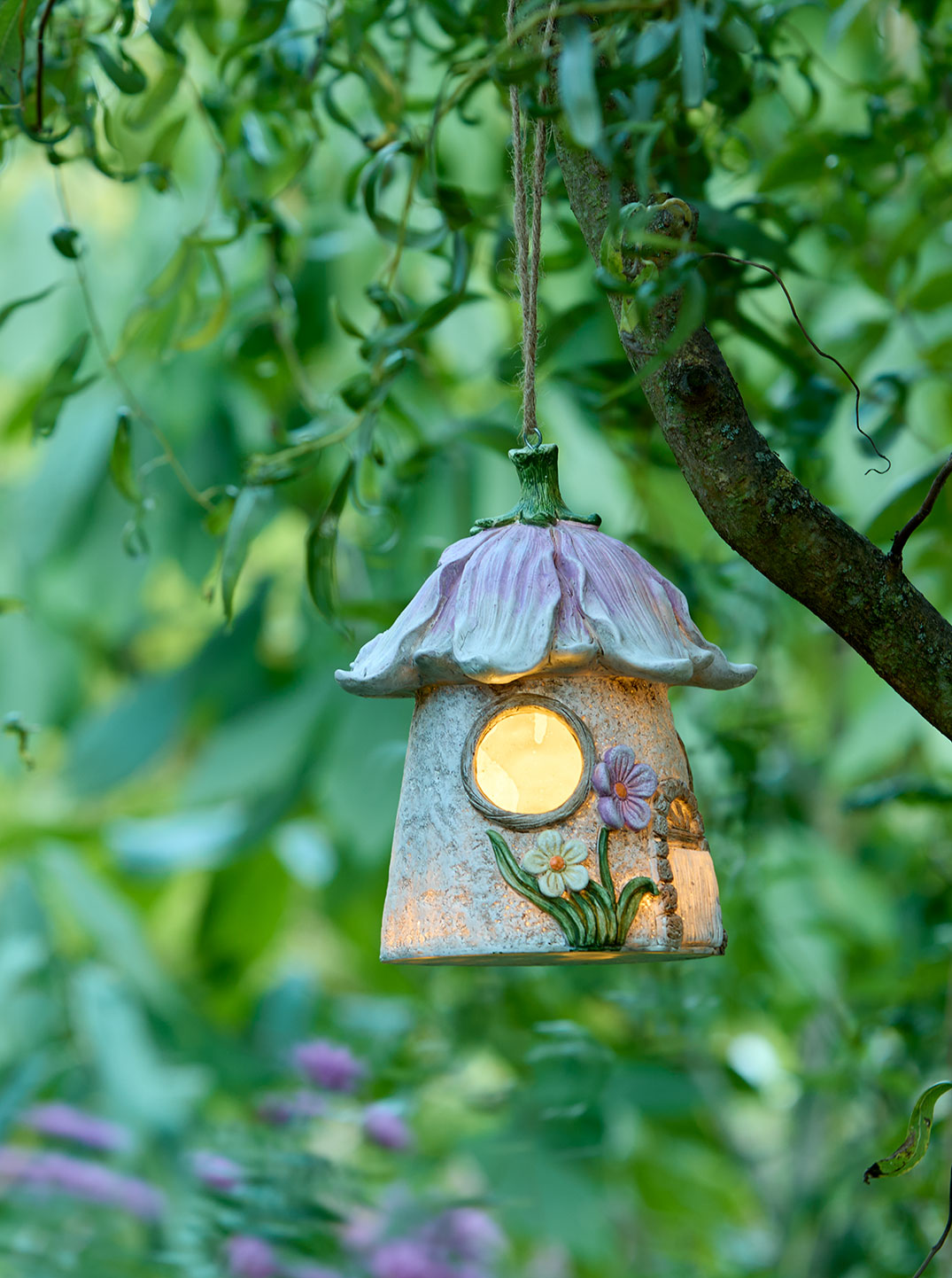 Ein märchenhaftes Solar-Elfenhaus hängt an einem Baumast und leuchtet warm. Umgeben von grünen Blättern entsteht eine verspielte, ruhige Atmosphäre voller Naturverbundenheit und sanfter Geborgenheit.