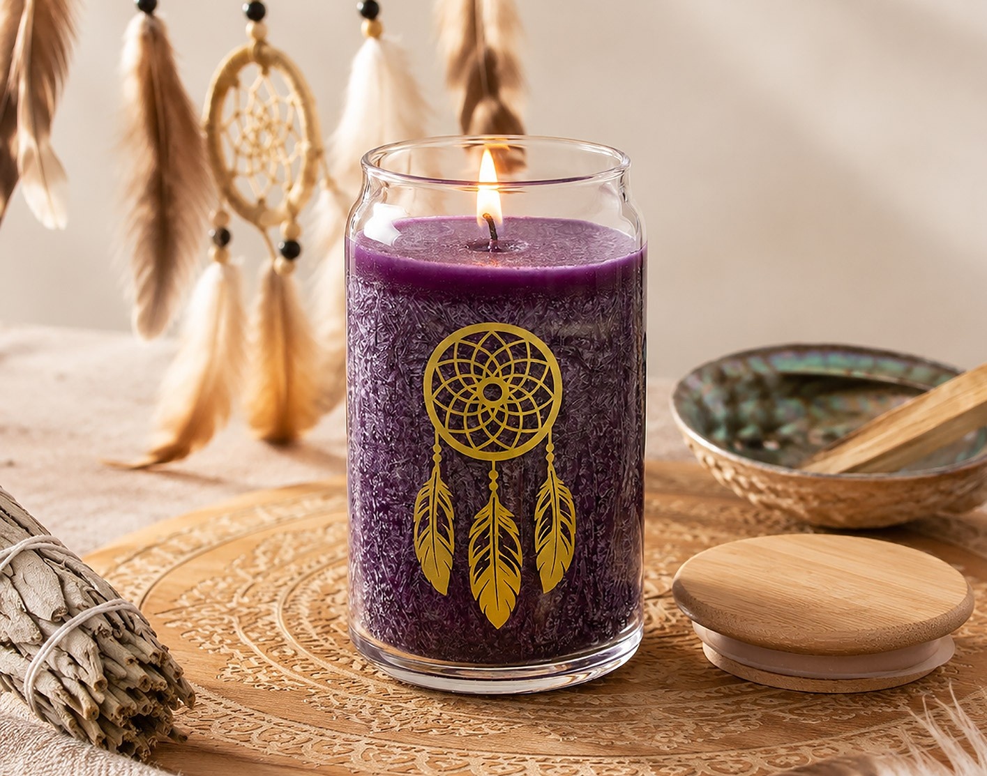 Violette Kerze im Glas mit goldenem Traumfänger-Motiv, umgeben von Federn, Räucherwerk und dekorativen Accessoires.