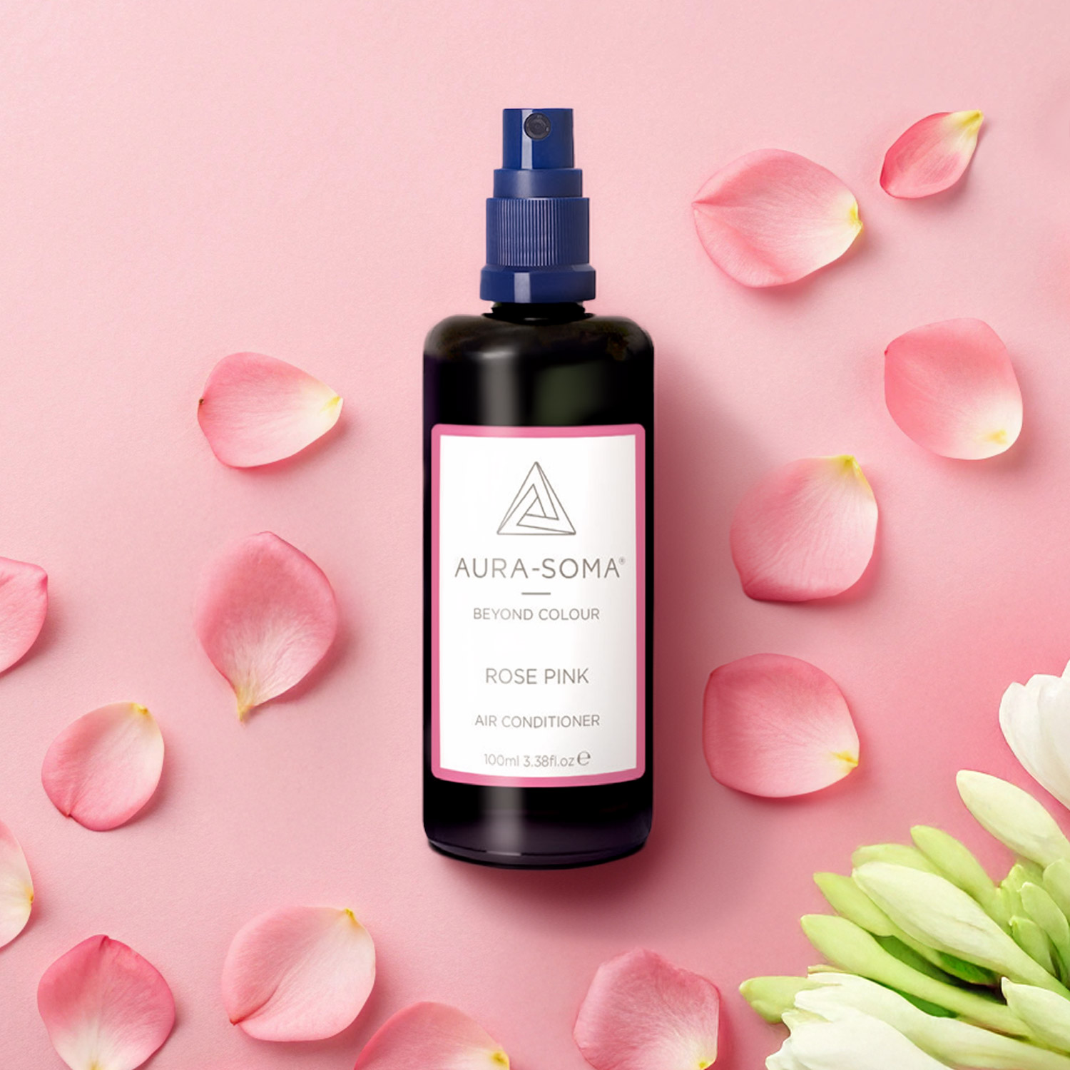Das Aura Soma Pomander Raumspray Rosenrosa liegt auf einem rosa Hintergrund, umgeben von Rosenblättern.