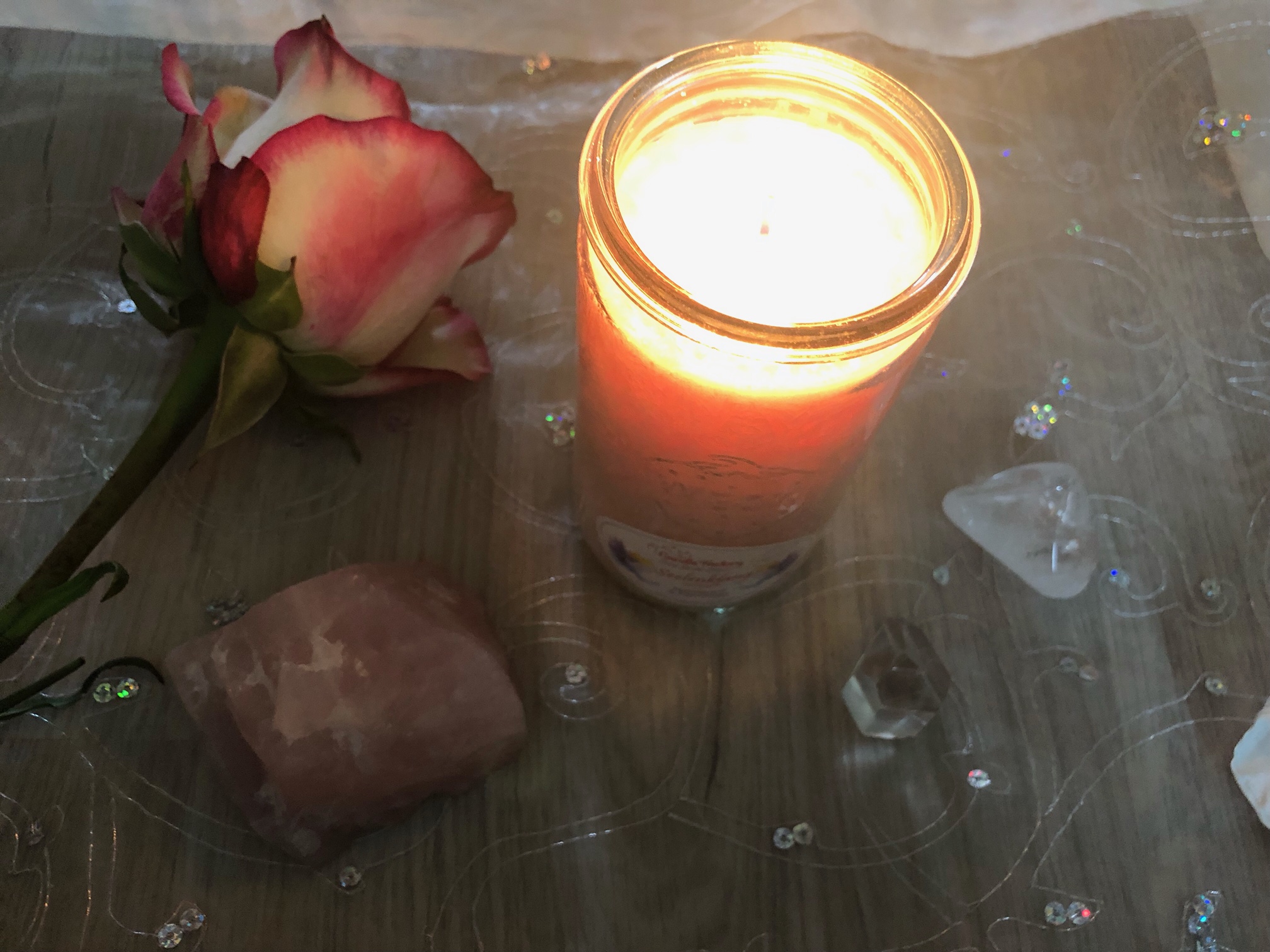 Brennende Kerze mit einem Rosenquarz und einer Rose