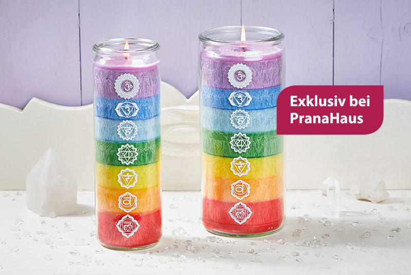 Zwei Kerzen im Weckglas, die jeweils in mehreren Schichten die Chakrafarben mit den dazugehörigen Symbolen zeigen. Daneben ein Label mit der Aufschrift "Exklusiv bei Pranahaus".